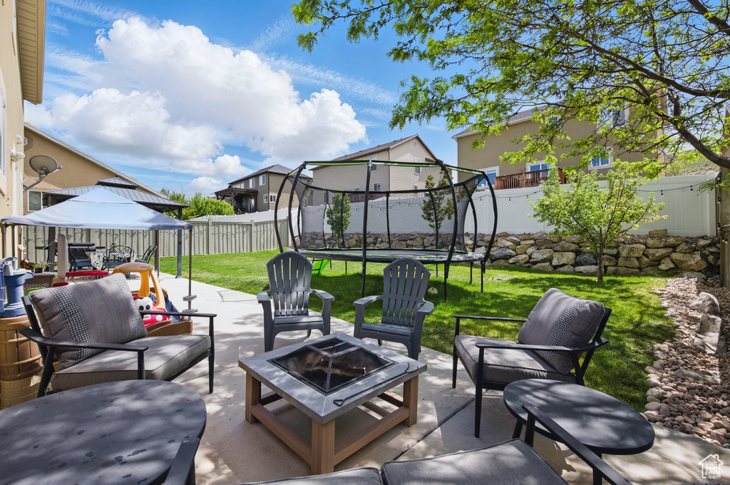 View of patio / terrace with a trampoline, a gazebo, a residential view, and an outdoor living space with a fire pit