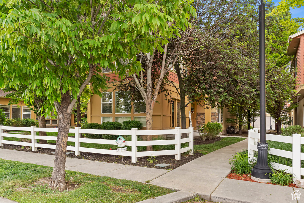 View of property hidden behind natural elements featuring a fenced front yard and stucco siding