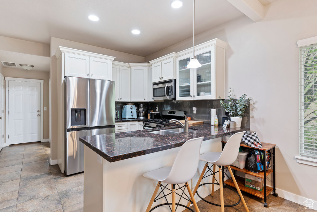 Kitchen with stainless steel appliances, a peninsula, baseboards, decorative backsplash, and glass insert cabinets