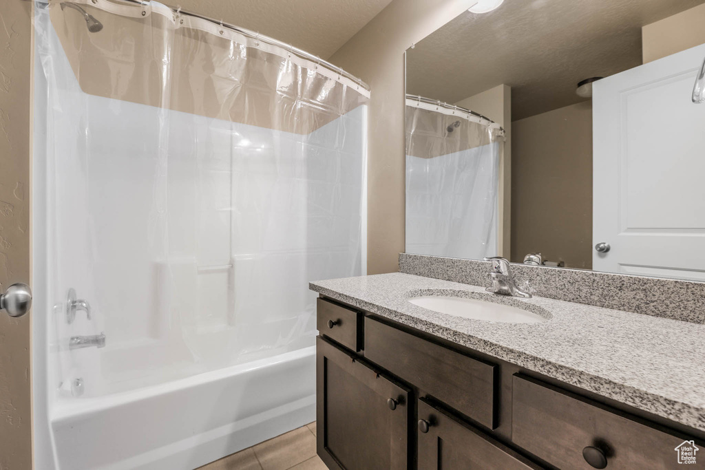 Bathroom with shower / bath combination with curtain, tile patterned flooring, and vanity