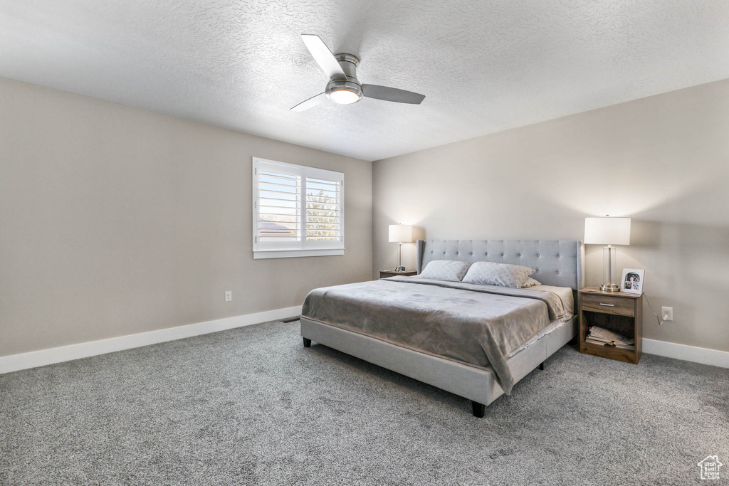 Bedroom with carpet, baseboards, a textured ceiling, and ceiling fan