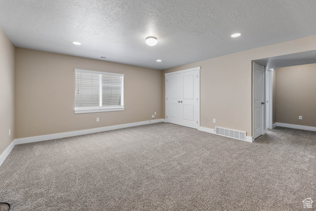 Unfurnished bedroom featuring a textured ceiling, baseboards, carpet, recessed lighting, and a closet