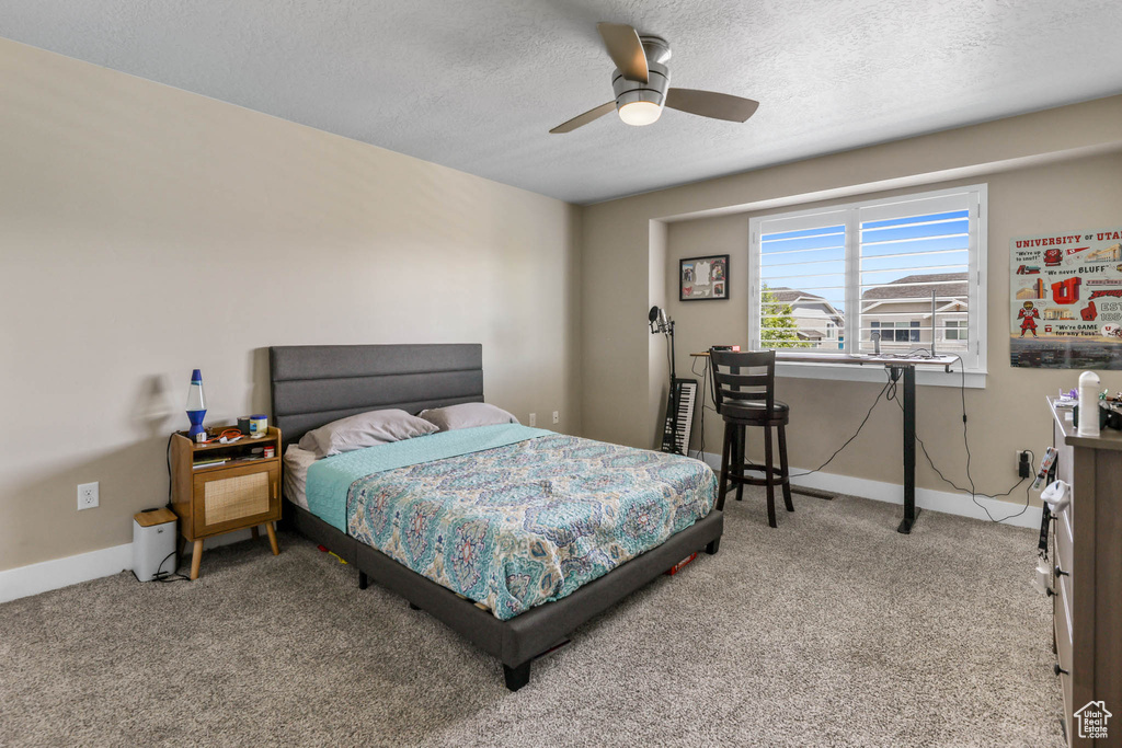 Bedroom with carpet floors, a textured ceiling, baseboards, an office area, and a ceiling fan