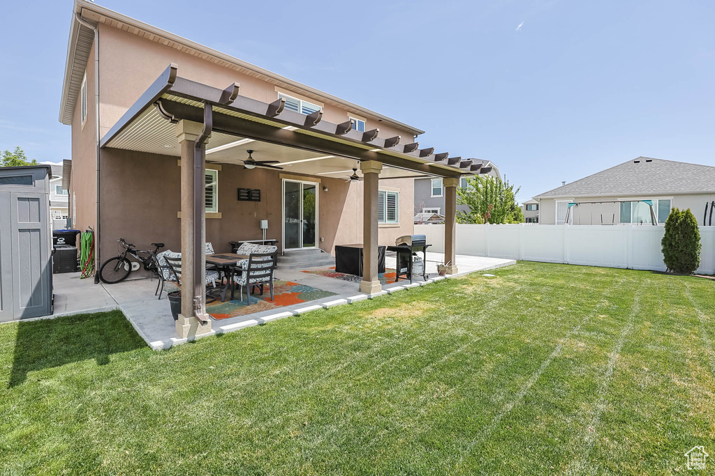Rear view of house with stucco siding, ceiling fan, and a patio area