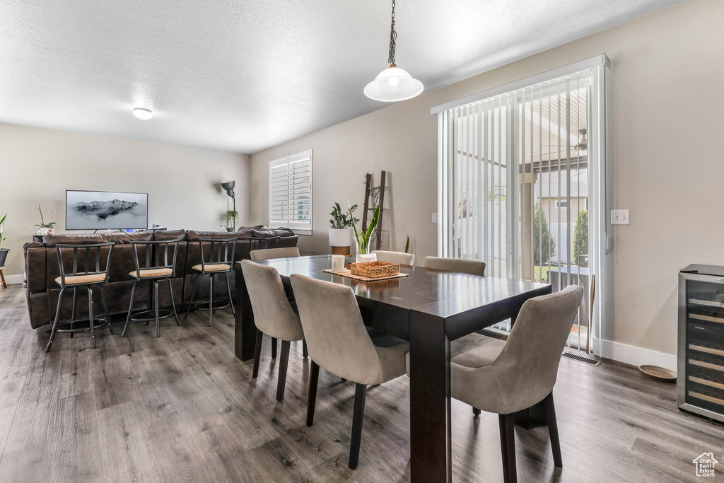 Dining space with beverage cooler, wood finished floors, and baseboards