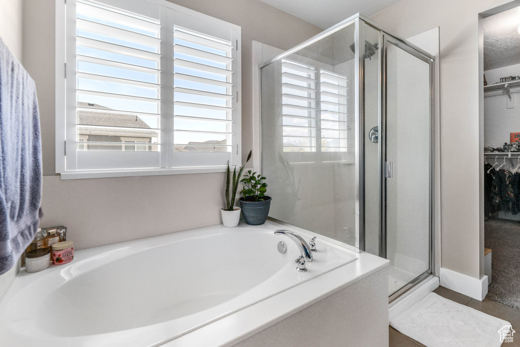 Full bath with a shower stall, a walk in closet, and a bath