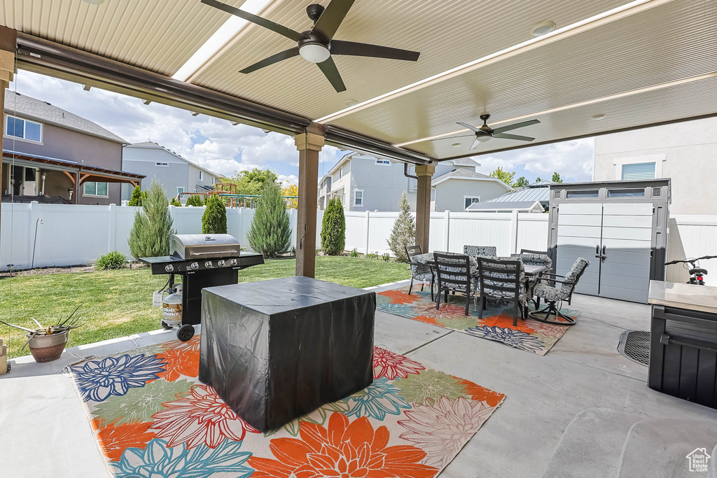 View of patio featuring area for grilling, outdoor dining space, ceiling fan, and a residential view