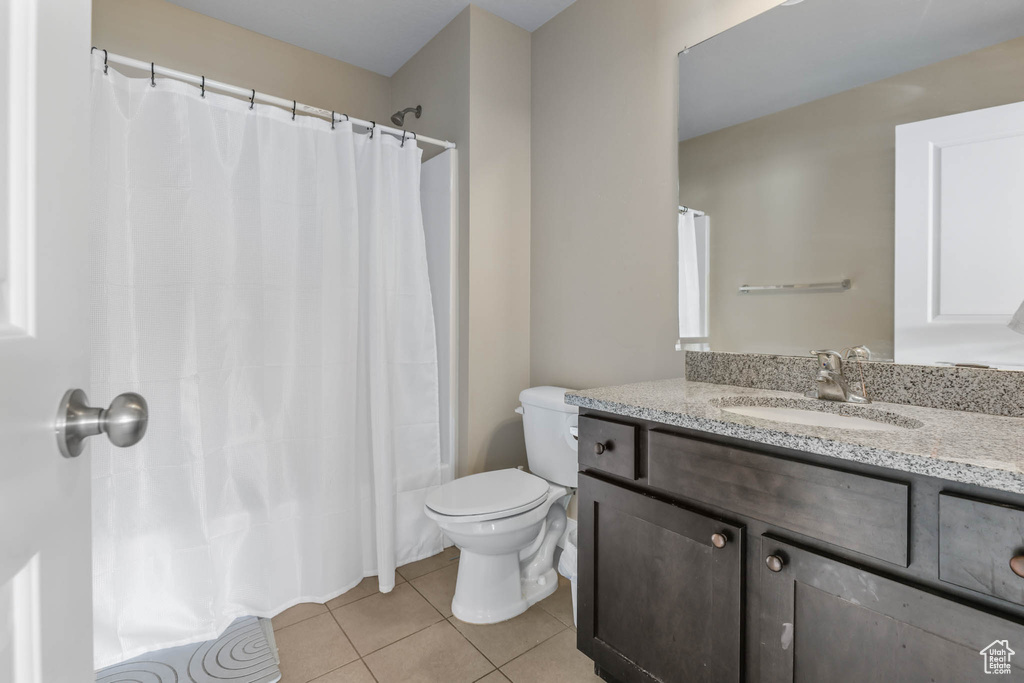 Full bath with tile patterned flooring, toilet, vanity, and a shower with shower curtain