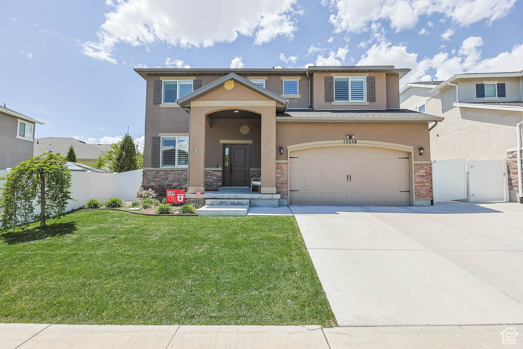 Traditional-style house with stone siding, a gate, driveway, and stucco siding