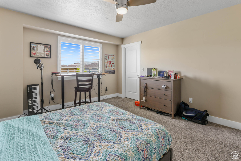 Carpeted bedroom with a textured ceiling, baseboards, and a ceiling fan