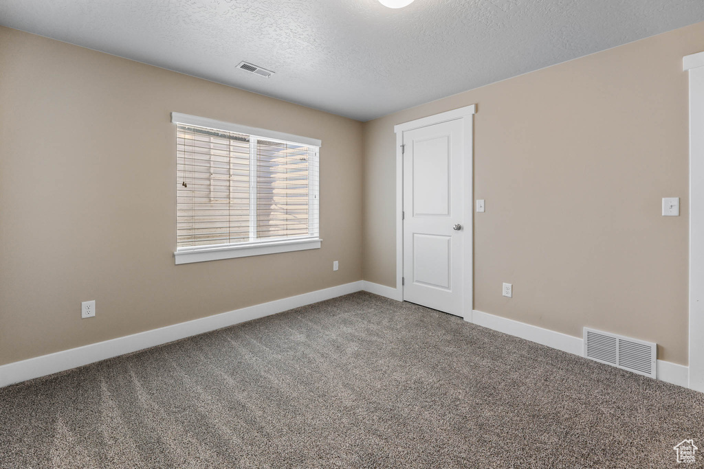 Unfurnished room featuring carpet flooring, a textured ceiling, and baseboards