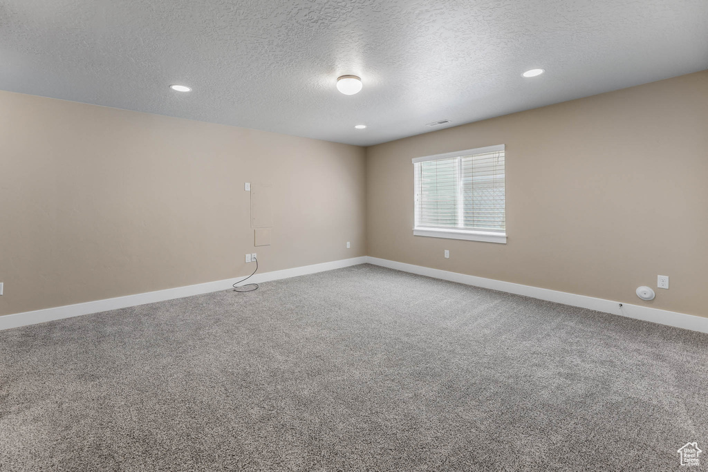 Empty room featuring a textured ceiling, baseboards, carpet floors, and recessed lighting