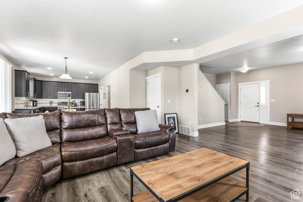 Living room featuring wood finished floors, baseboards, recessed lighting, and a textured ceiling