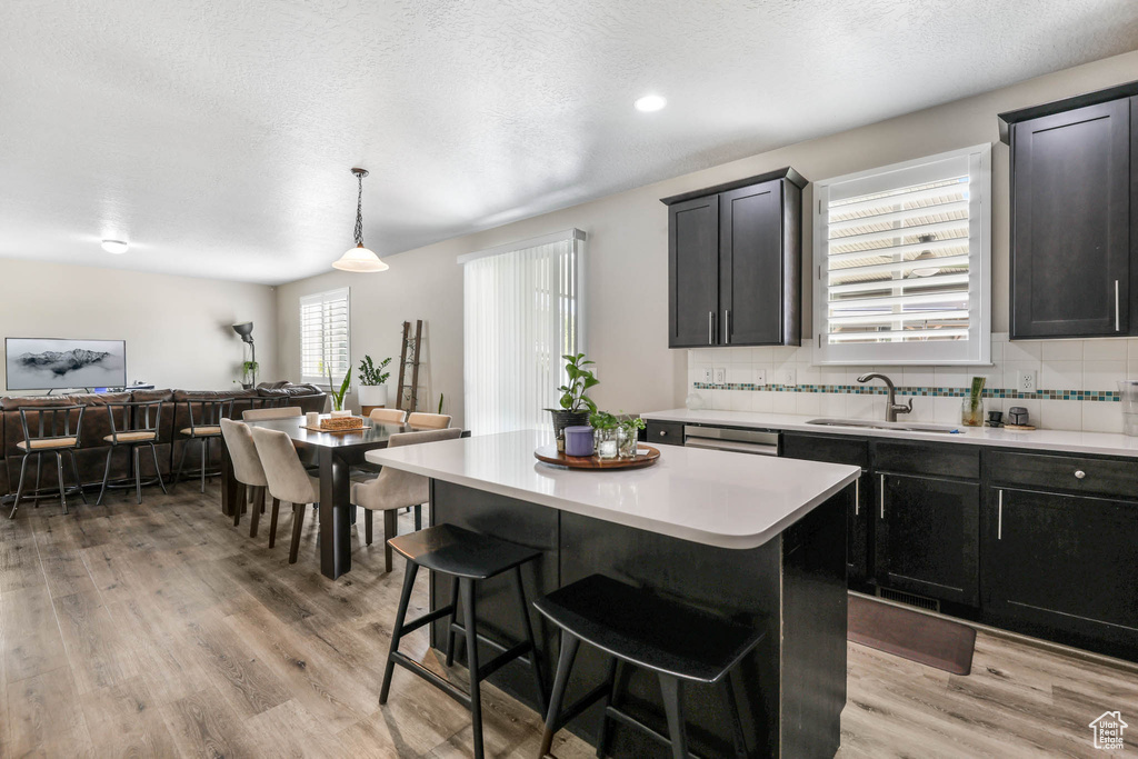 Kitchen featuring a sink, light countertops, a breakfast bar, a kitchen island, and recessed lighting