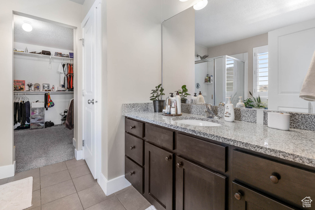 Bathroom featuring a shower stall, tile patterned floors, vanity, a spacious closet, and baseboards