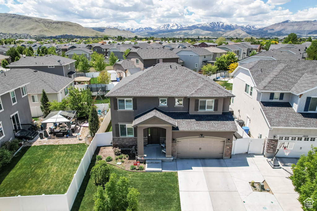 Traditional home featuring stucco siding, a residential view, driveway, an attached garage, and stone siding