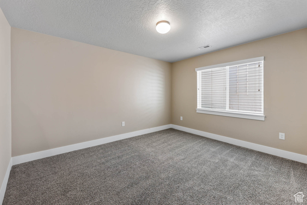 Spare room with a textured ceiling, carpet, and baseboards