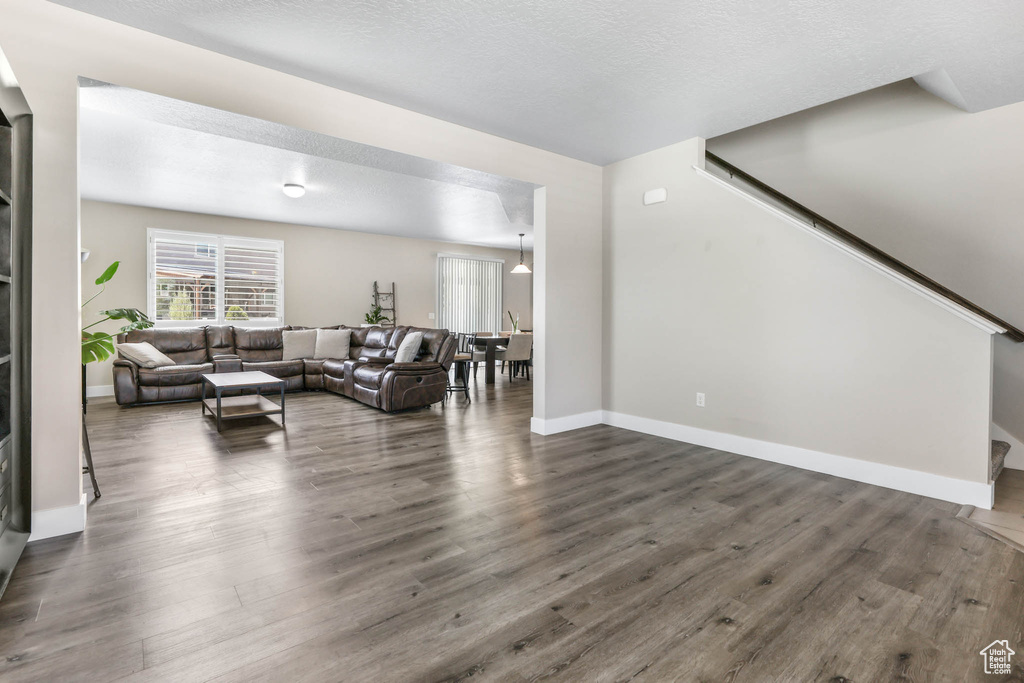 Living area with dark wood-type flooring, stairs, baseboards, and a textured ceiling
