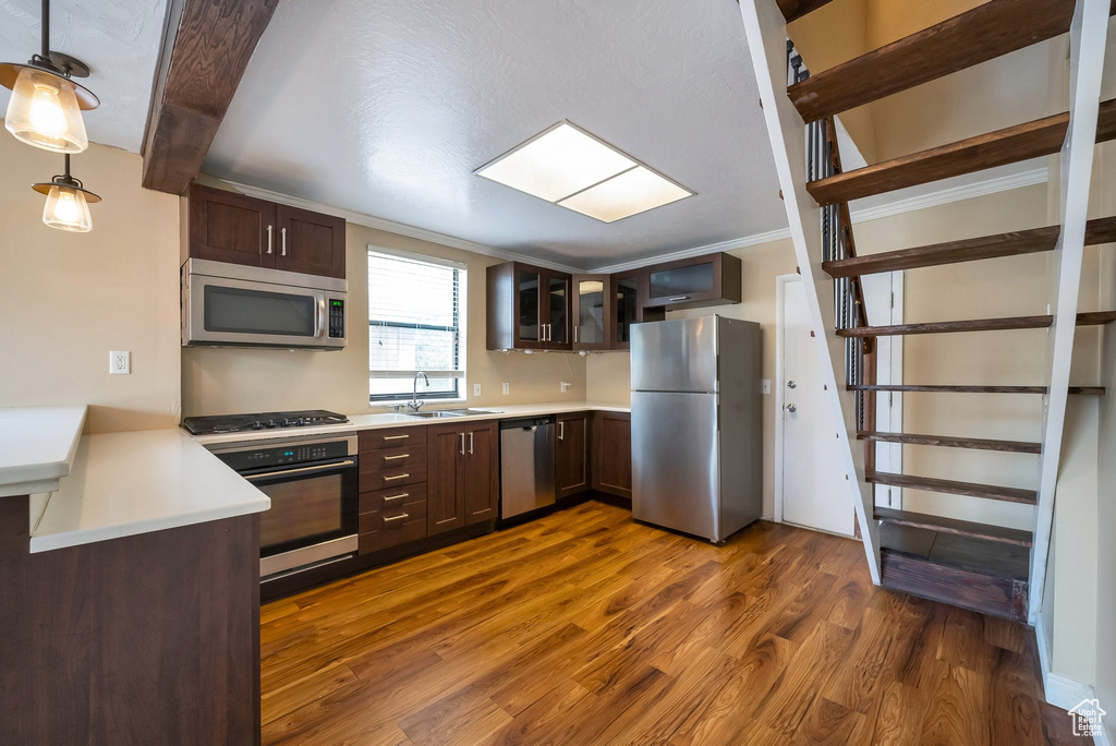 Kitchen featuring appliances with stainless steel finishes, dark wood-style floors, dark brown cabinets, open shelves, and light countertops