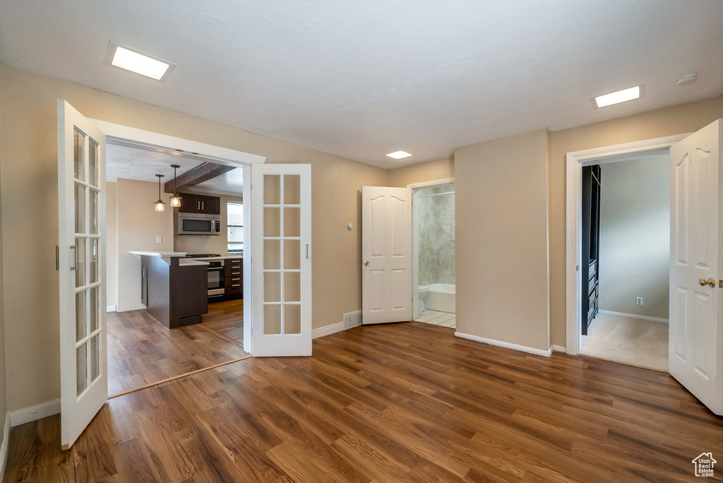Empty room with french doors, dark wood-style flooring, and baseboards