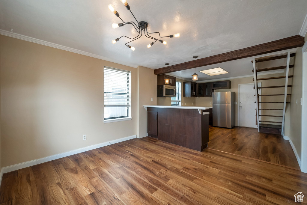 Kitchen with stainless steel appliances, a peninsula, dark wood-type flooring, light countertops, and a chandelier