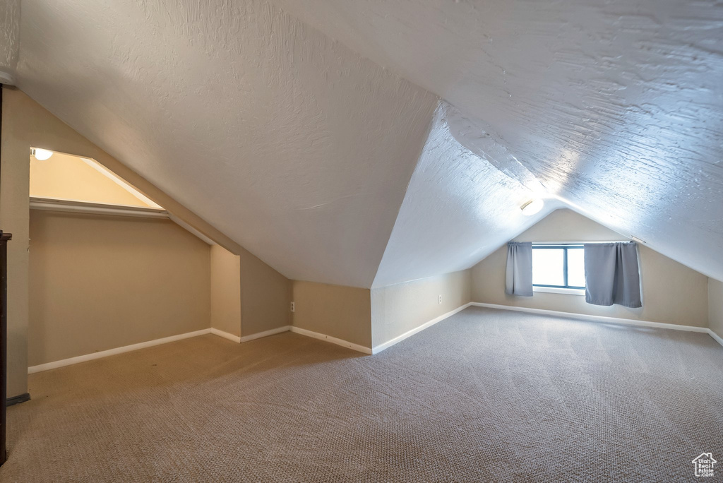 Bonus room featuring baseboards, vaulted ceiling, a textured ceiling, and carpet