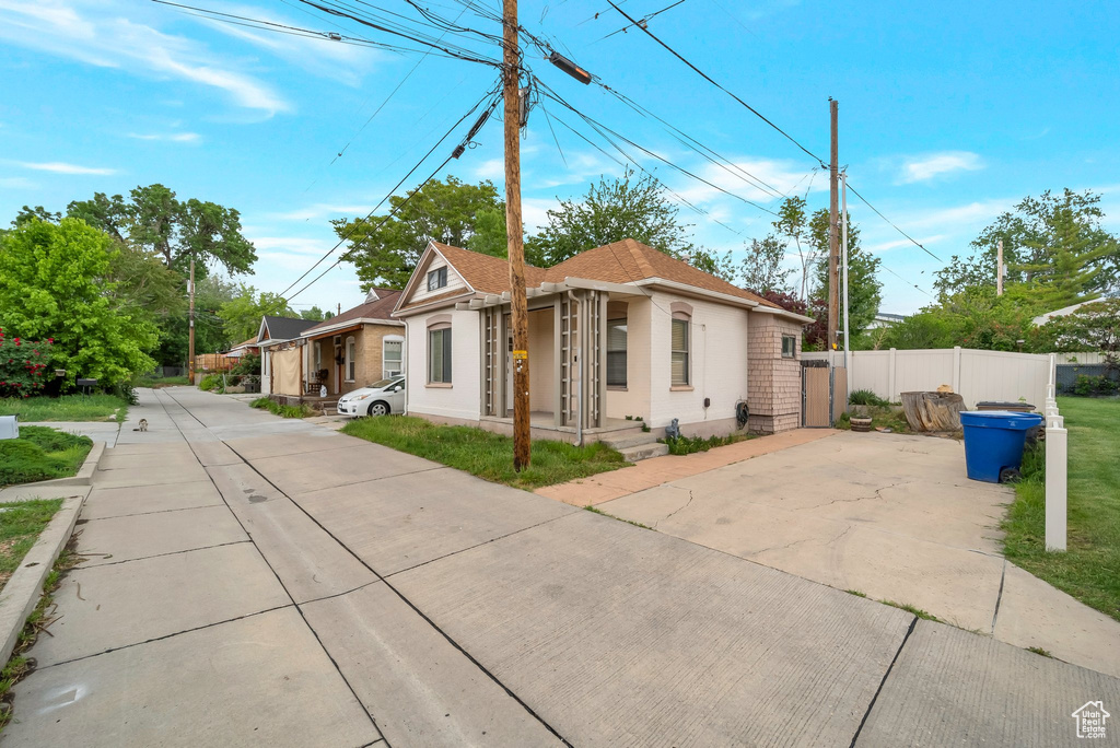 View of front of house with concrete driveway, fence, and stucco siding