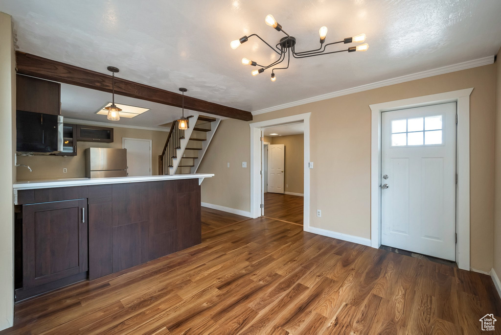 Kitchen with freestanding refrigerator, crown molding, wood finished floors, baseboards, and light countertops