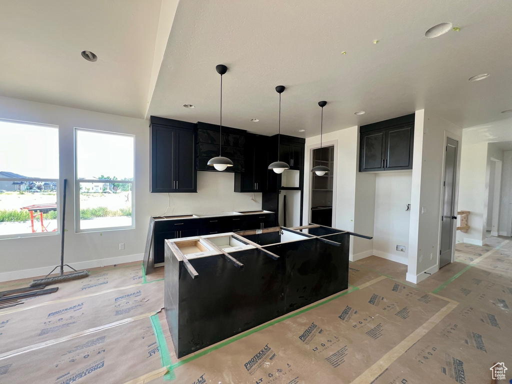 Kitchen featuring baseboards, a kitchen island, dark cabinets, and recessed lighting