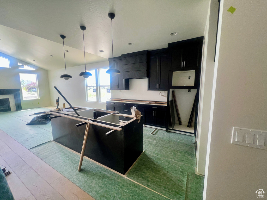 Kitchen with dark cabinetry, healthy amount of natural light, range hood, and hanging light fixtures