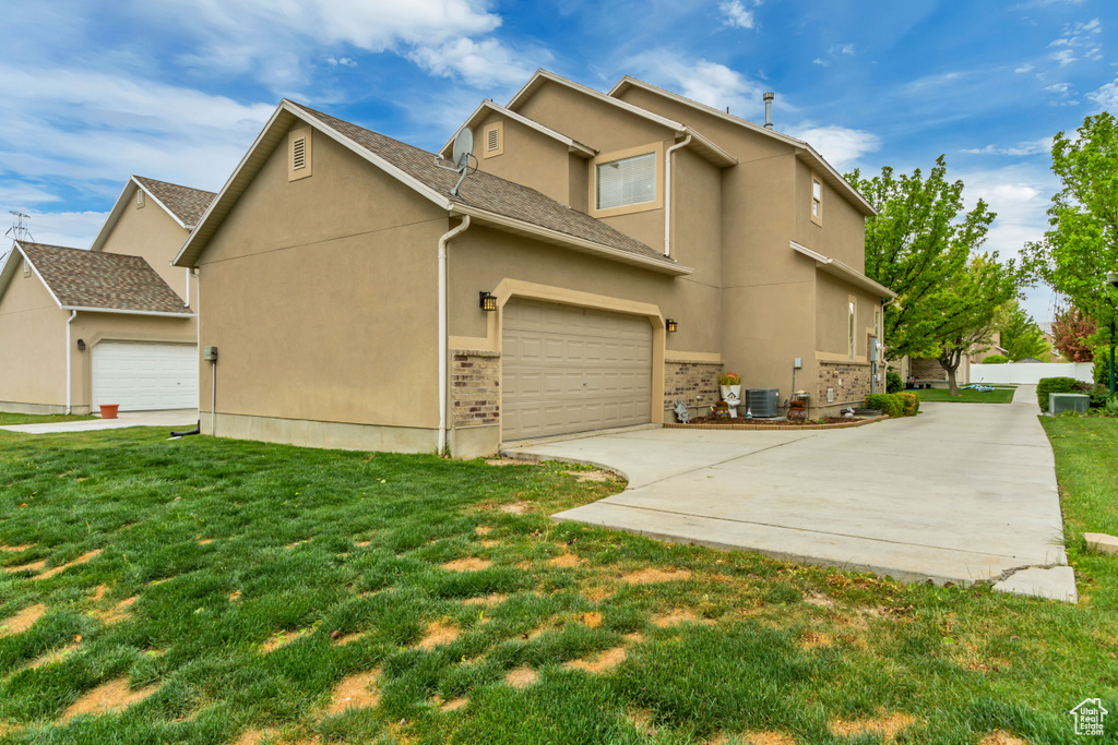 View of property exterior featuring driveway, stucco siding, a lawn, and central AC unit