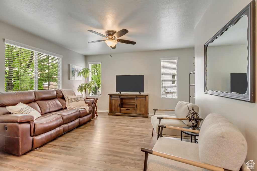 Living area featuring a ceiling fan, light wood finished floors, and baseboards
