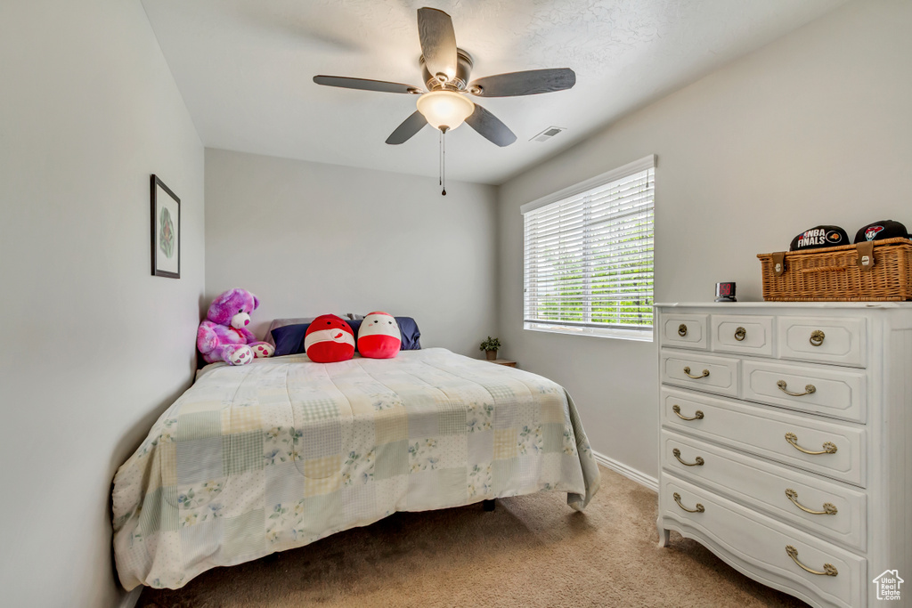 Bedroom with light colored carpet, ceiling fan, and baseboards