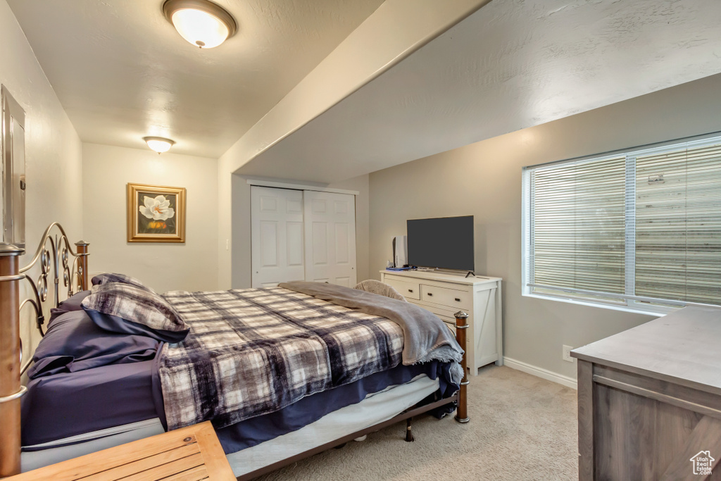 Bedroom featuring light carpet, a closet, and baseboards