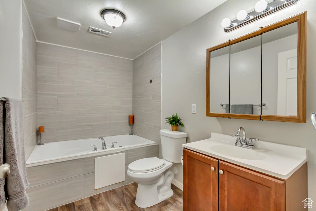 Full bath with wood finished floors, toilet, a tub, and vanity