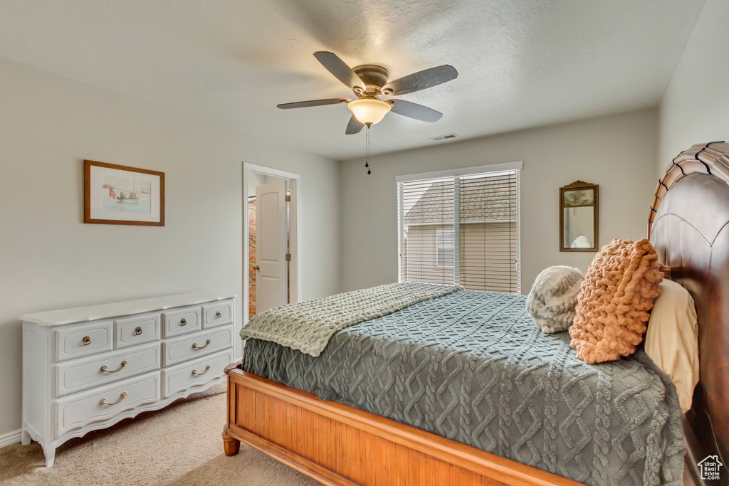 Bedroom featuring light carpet, a ceiling fan, ensuite bath, and baseboards