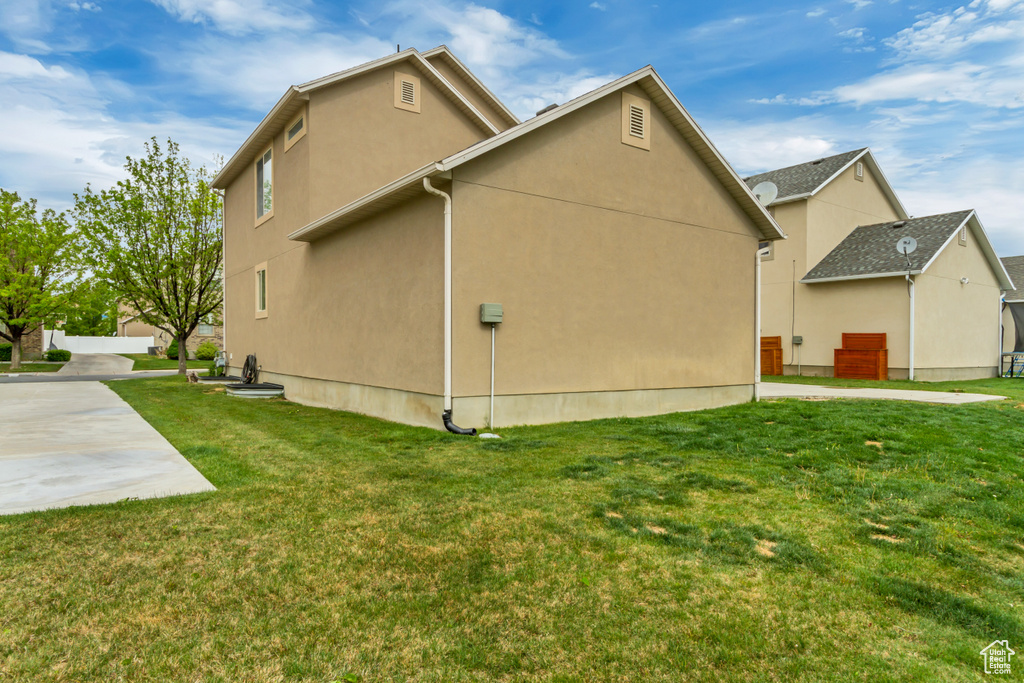 View of property exterior with a lawn and stucco siding