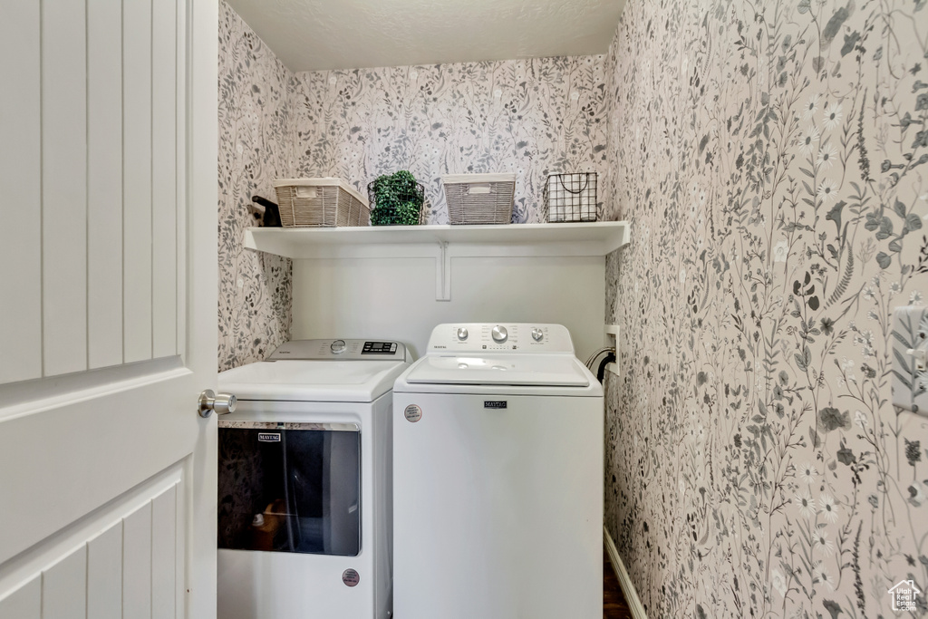 Laundry area featuring washing machine and dryer and wallpapered walls