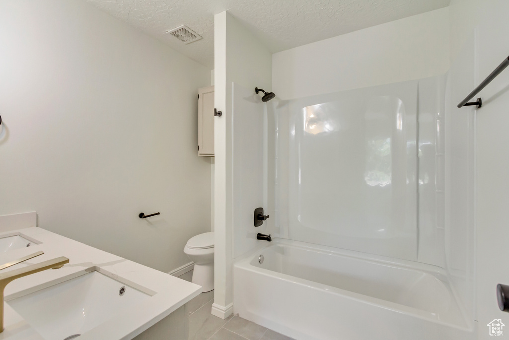 Bathroom with vanity, a textured ceiling, toilet, tile patterned floors, and shower / bathtub combination