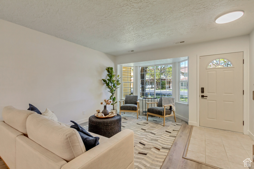 Entryway with a textured ceiling, light wood-style flooring, and baseboards