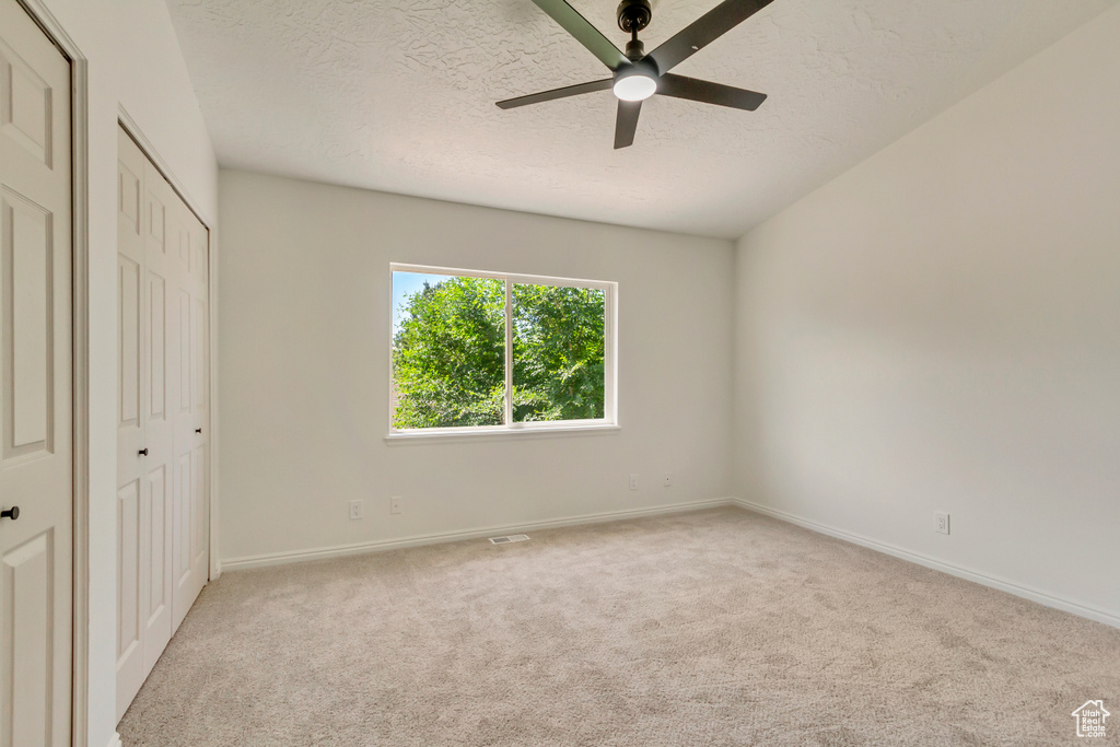 Unfurnished bedroom with carpet, a textured ceiling, baseboards, a ceiling fan, and a closet