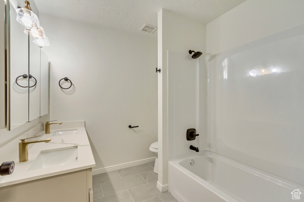 Full bath with toilet, shower / tub combination, double vanity, tile patterned flooring, and a textured ceiling