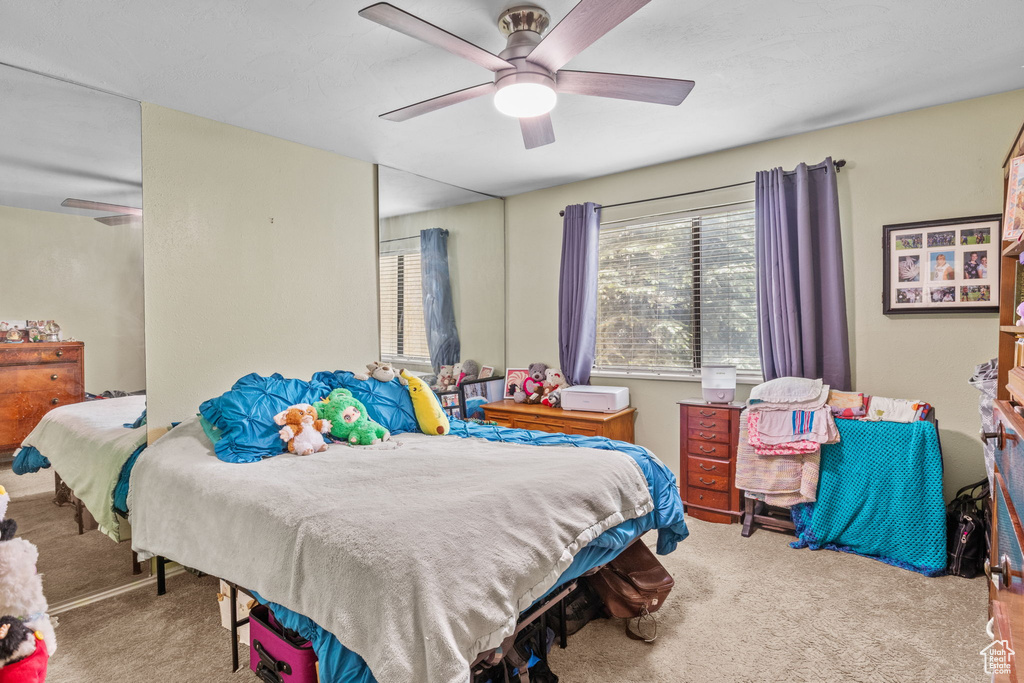 Carpeted bedroom with a ceiling fan