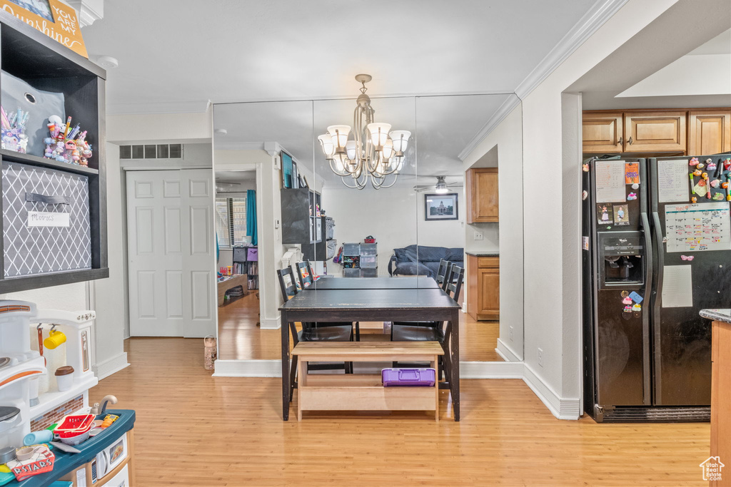 Dining space with light wood-style floors, a chandelier, ornamental molding, and baseboards