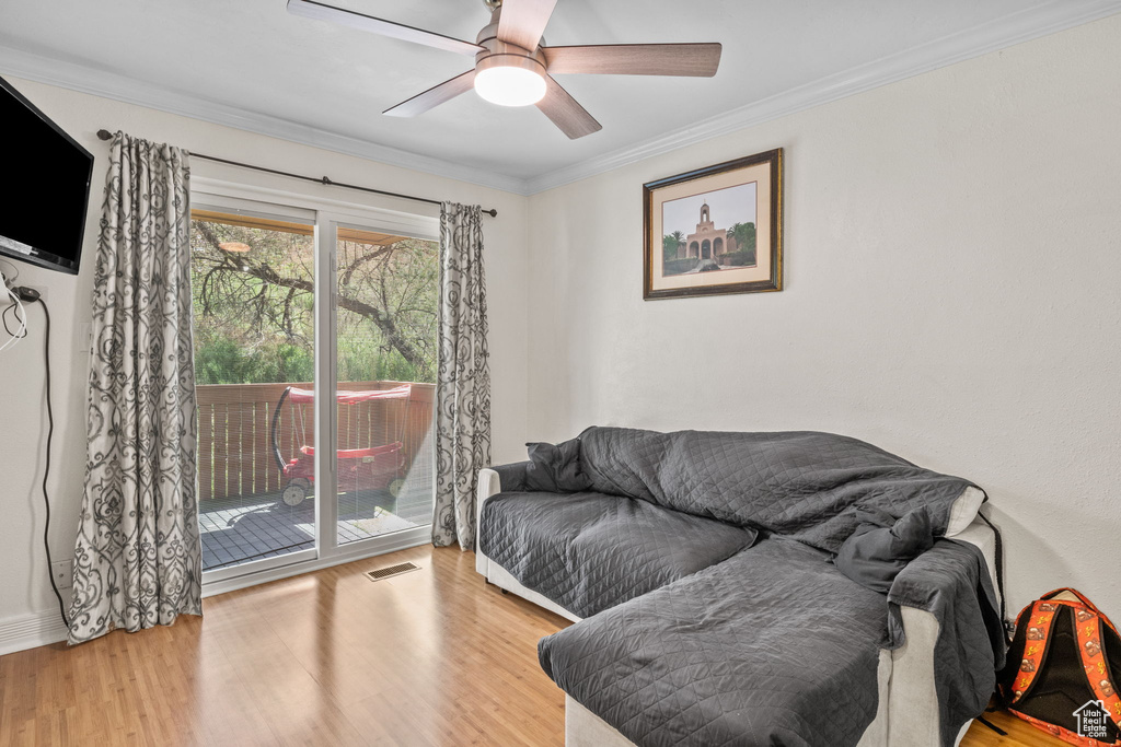 Living room with wood finished floors, crown molding, a ceiling fan, and baseboards
