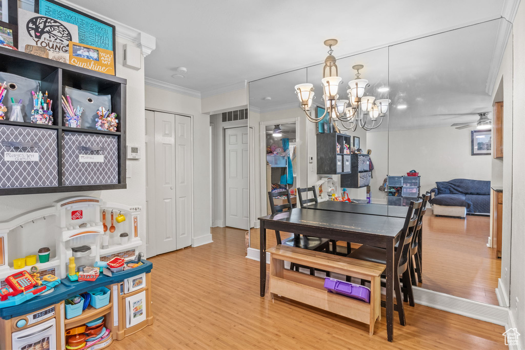 Dining area with wood finished floors, a chandelier, ceiling fan, crown molding, and baseboards
