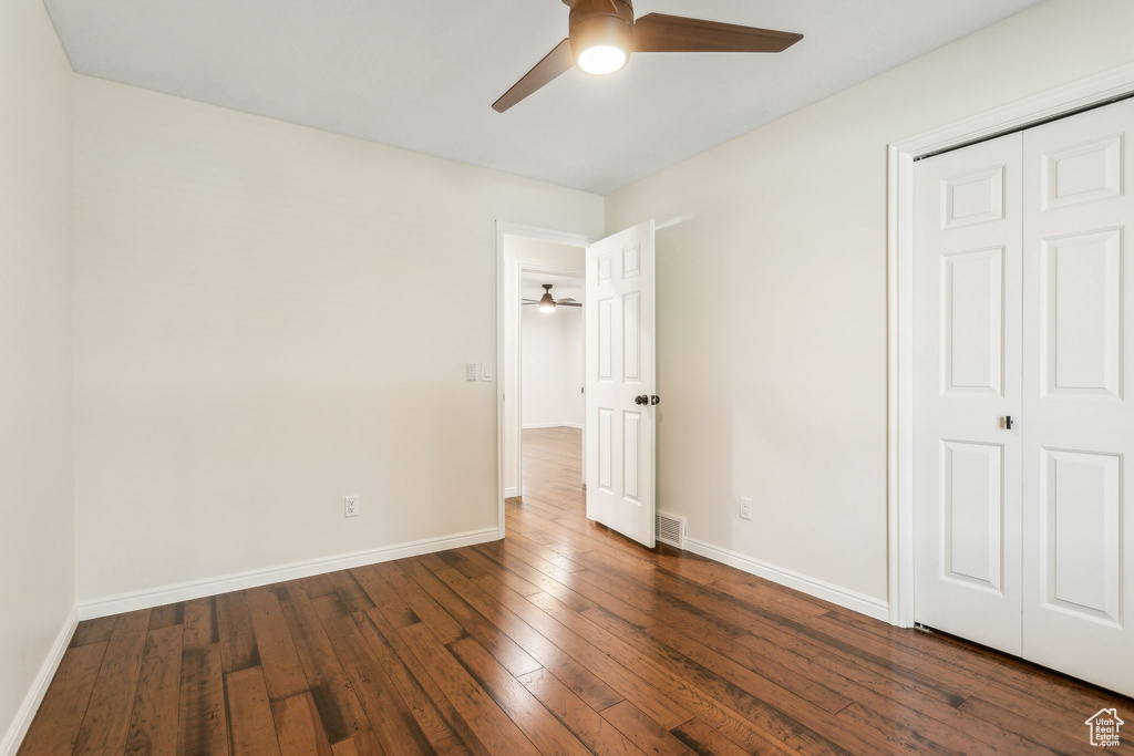 Unfurnished bedroom featuring a closet, wood-type flooring, baseboards, and a ceiling fan