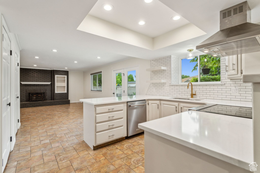 Kitchen with wall chimney range hood, healthy amount of natural light, dishwasher, a peninsula, and recessed lighting