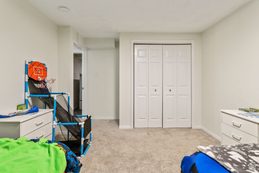 Bedroom with light carpet, a closet, and baseboards