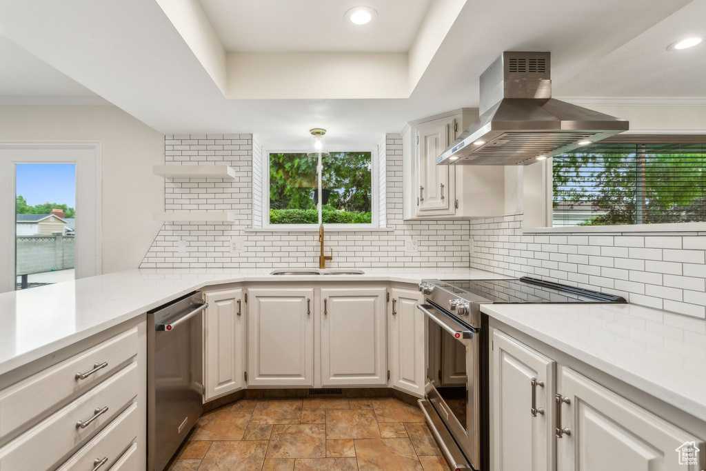 Kitchen featuring ventilation hood, appliances with stainless steel finishes, light countertops, a sink, and backsplash